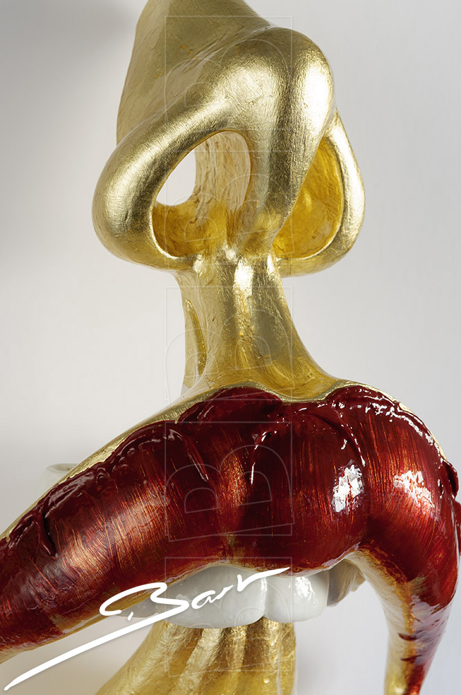 Sculptuur van open mond met tong en neus in goud en rood. Sculpture of open mouth with tongs and nose in gold colour and red.