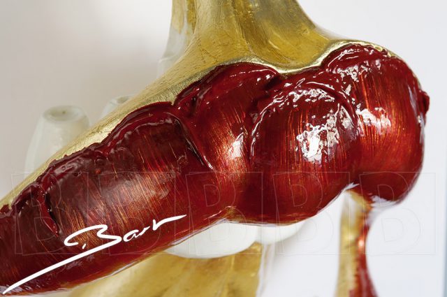 Sculptuur van open mond met tong en neus in goud en rood. Sculpture of open mouth with tongs and nose in gold colour and red.