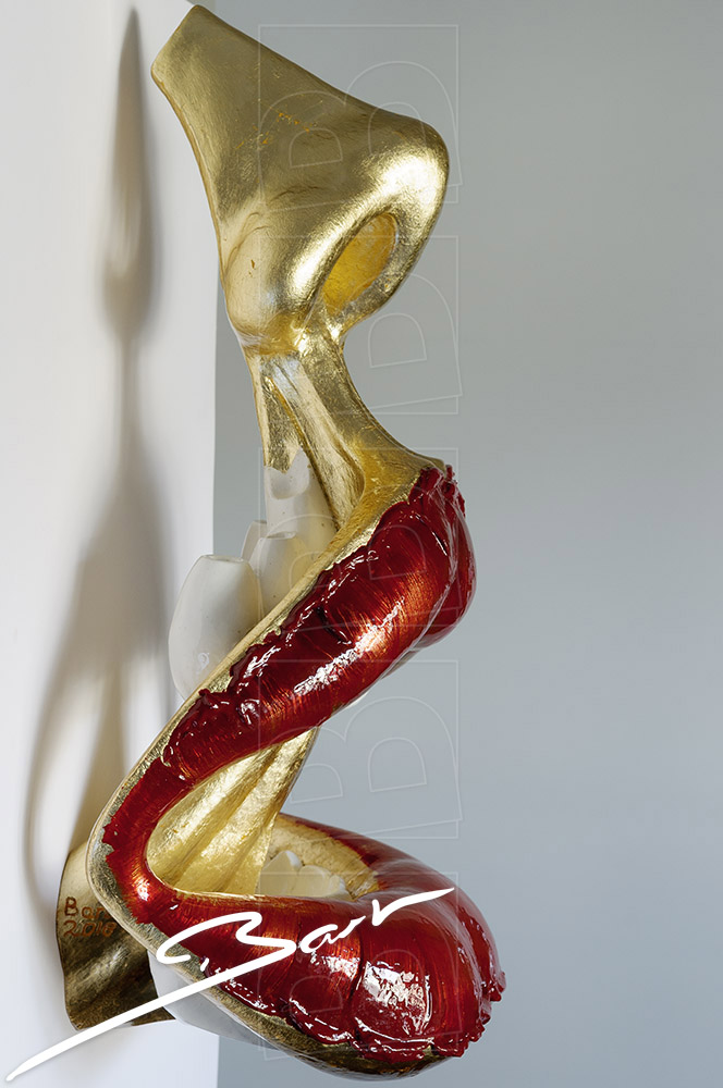 Sculptuur van open mond met tong en neus in goud en rood. Sculpture of open mouth with tongs and nose in gold colour and red.